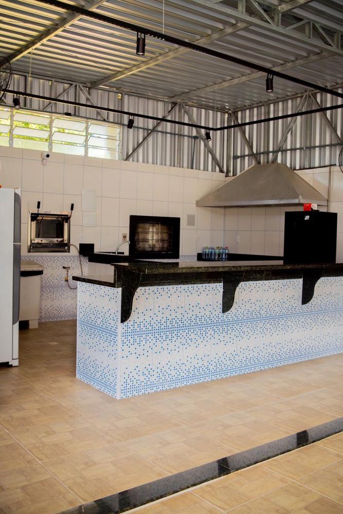 Cozinha com churrasqueira, bancada de granito e revestimento em mosaico azul