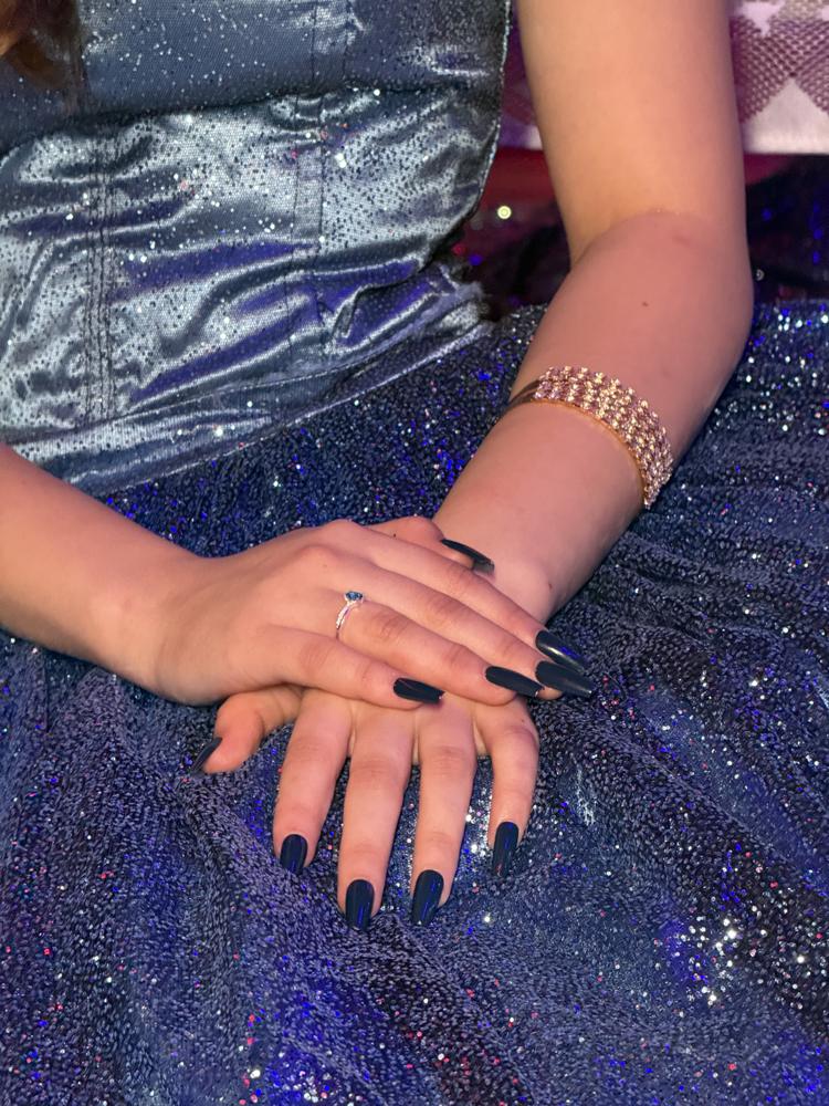 Detalhe das mãos da debutante sobre o vestido azul com brilho