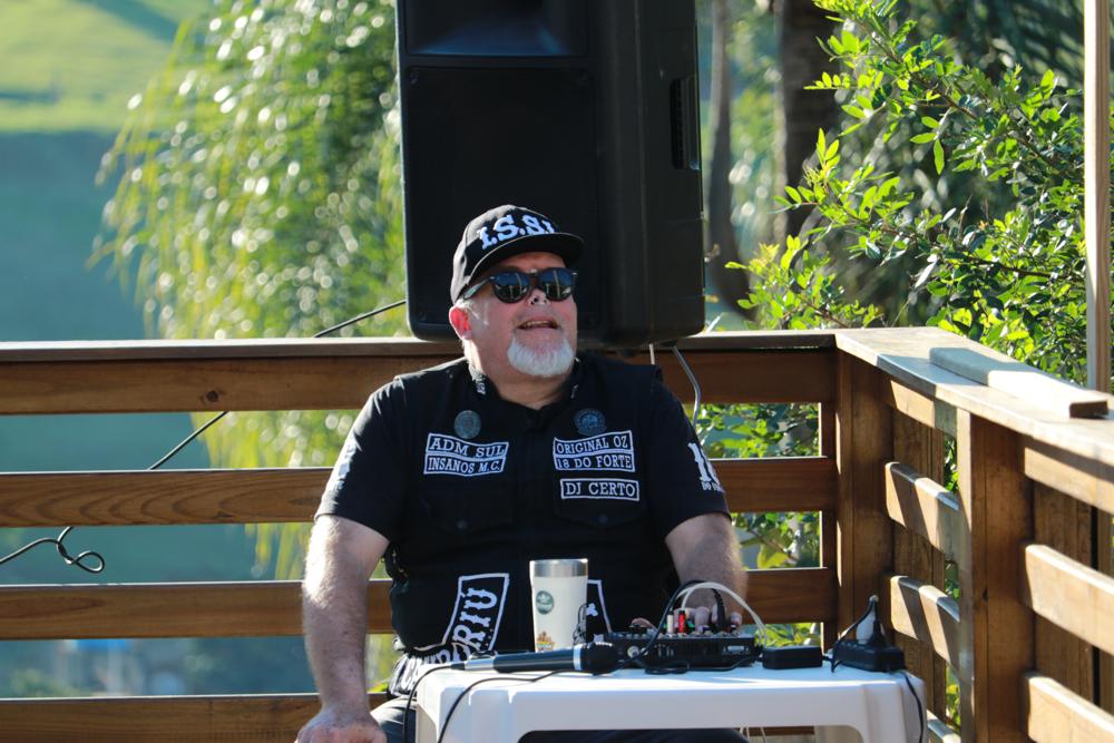 DJ tocando no deck com vegetação ao fundo