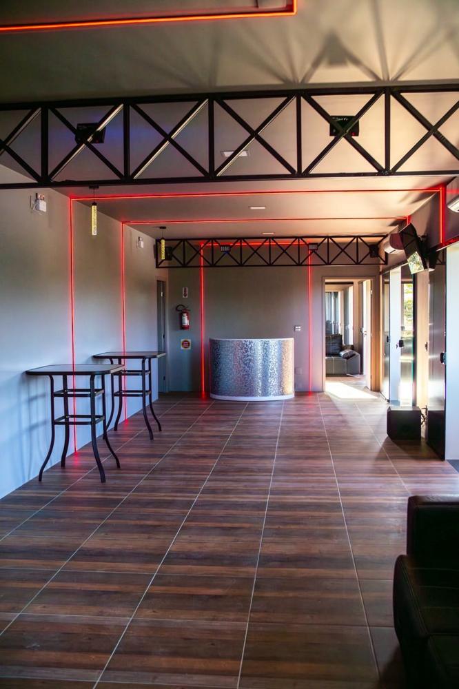 Espaço Balada com piso de madeira, estrutura de treliça e luz vermelha