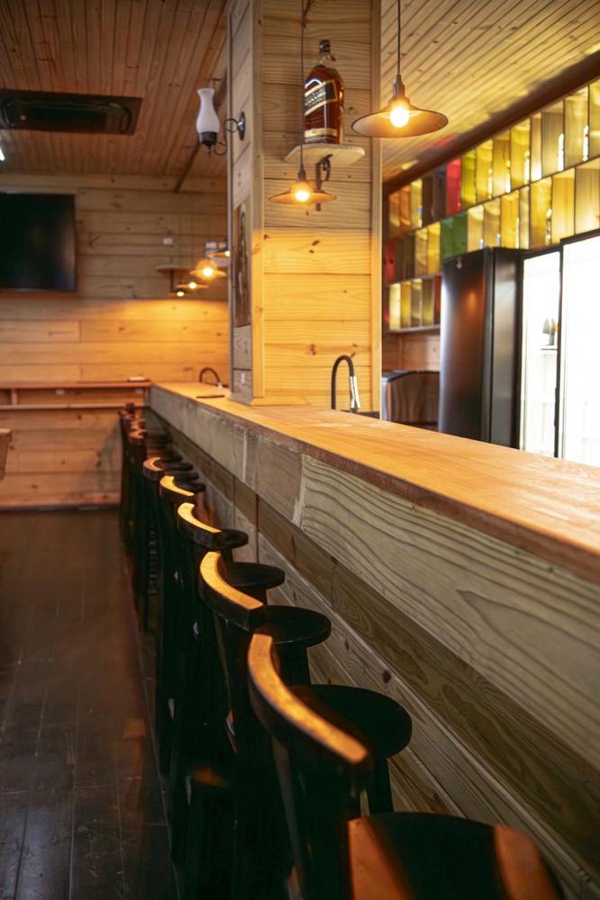 Balcão de madeira do saloon com banquetas e luminárias