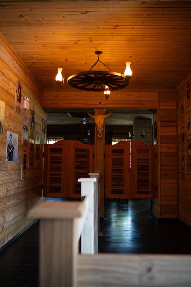 Entrada do Middle River Saloon com portas vai e vem e lustre de roda de carroça
