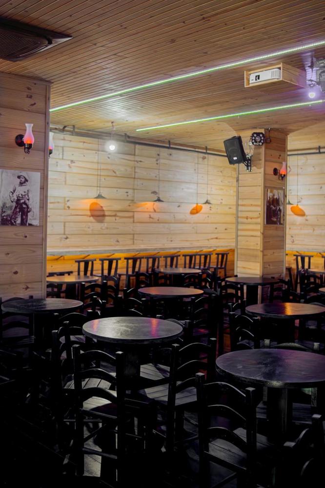 Salão do saloon com mesas redondas e paredes de madeira